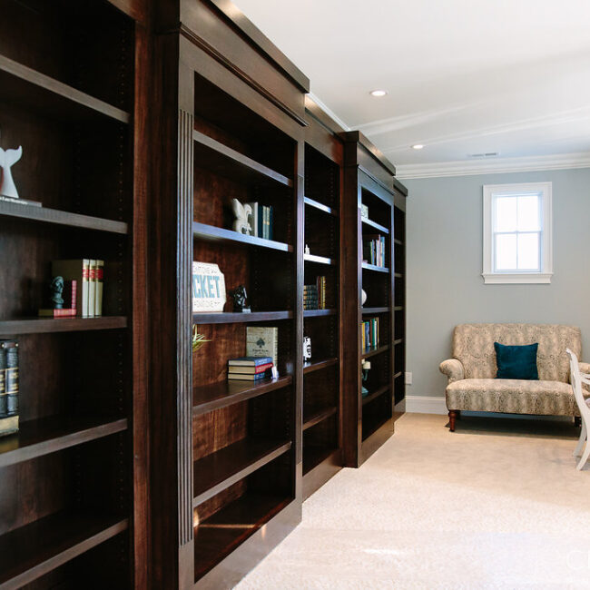Dark wood built-in bookshelves beside a sitting room sofa in Haunted Mansion Homage, a custom home by Mike Stevens Homes