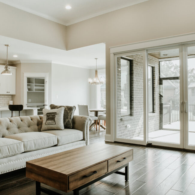 Open living room with glass doors to sunroom in Timeless Charm, a custom home by Mike Stevens Homes