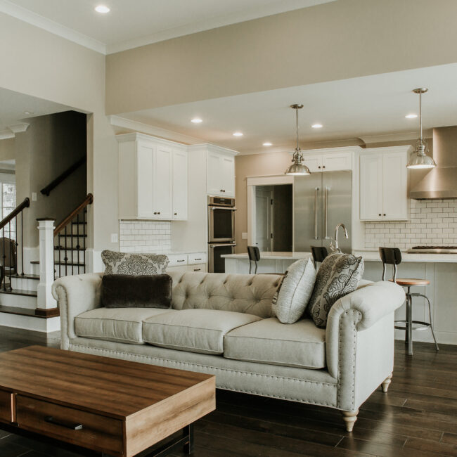 Living room with tufted sofa and wood coffee table in Timeless Charm, a custom home by Mike Stevens Homes