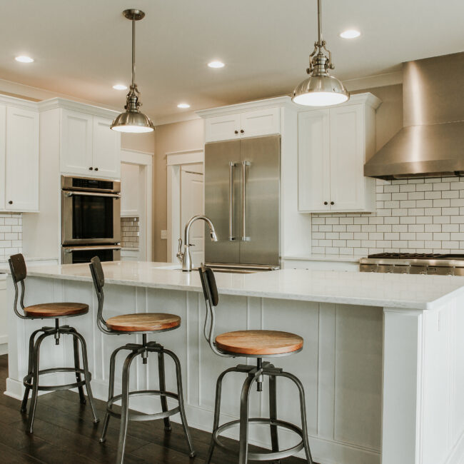Kitchen with white cabinets, pendants, and stainless fridge in Timeless Charm, a custom home by Mike Stevens Homes