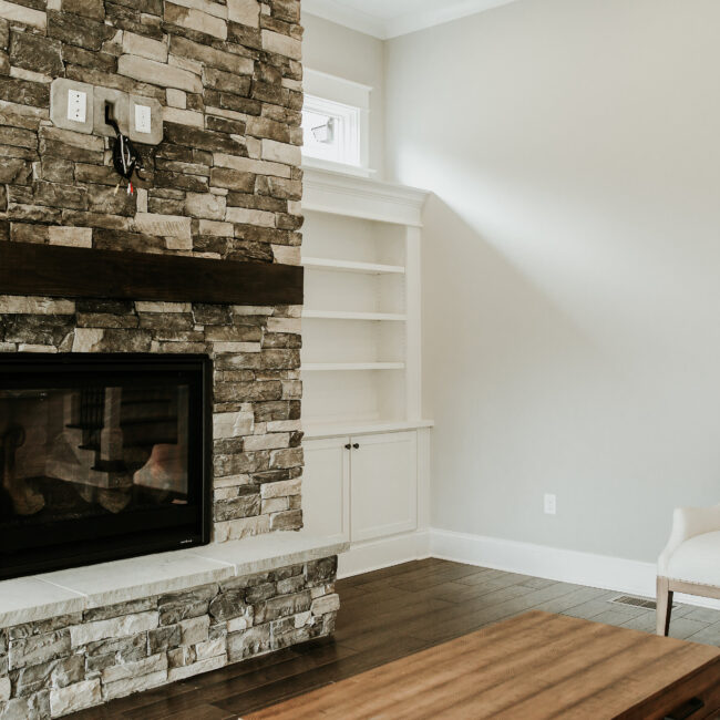 Stone fireplace with gas insert and built-in shelves in Timeless Charm, a custom home by Mike Stevens Homes