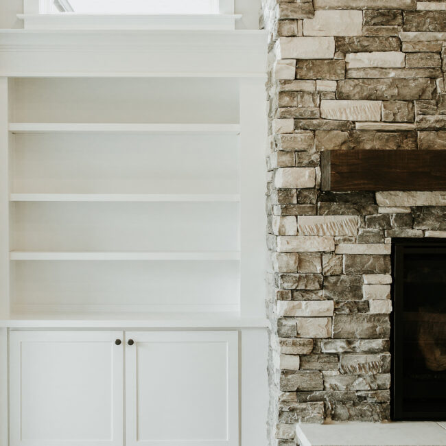 Built-in white shelving beside stone fireplace in Timeless Charm, a custom home by Mike Stevens Homes