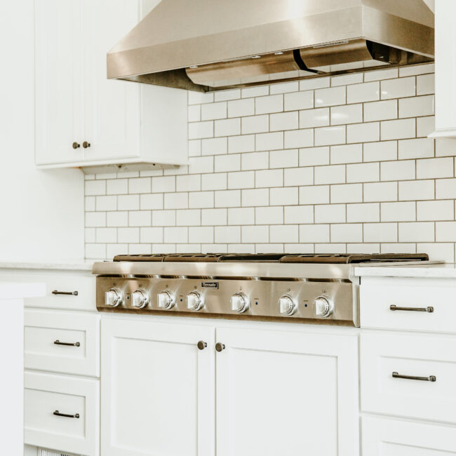 Kitchen with white subway backsplash and range hood in Timeless Charm, a custom home by Mike Stevens Homes