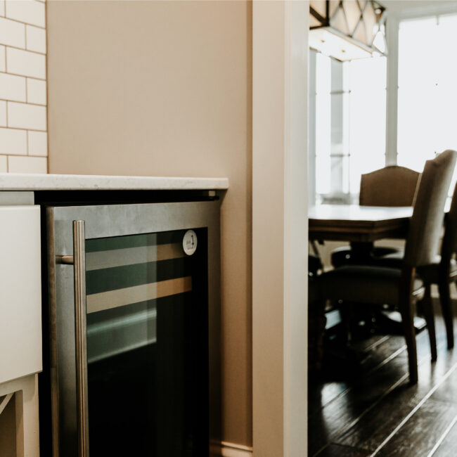 Kitchen with beverage fridge and dining nook beyond in Timeless Charm, a custom home by Mike Stevens Homes