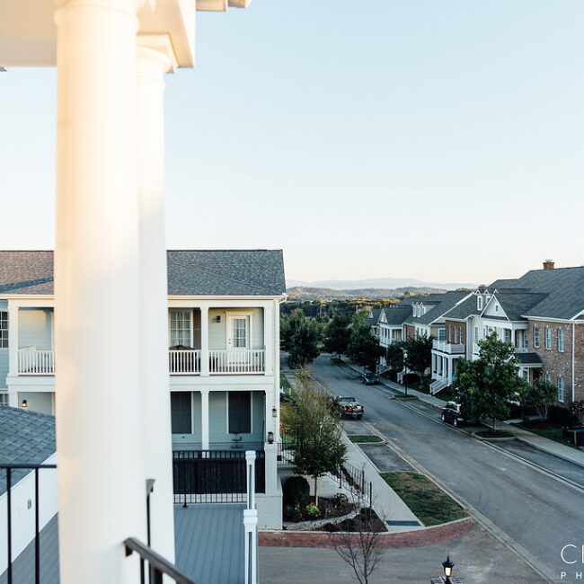 Upper balcony view down a street of columned homes in Haunted Mansion Homage, a custom home by Mike Stevens Homes