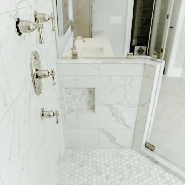 Shower with marble-look tile and hex floor niche in Timeless Charm, a custom home by Mike Stevens Homes