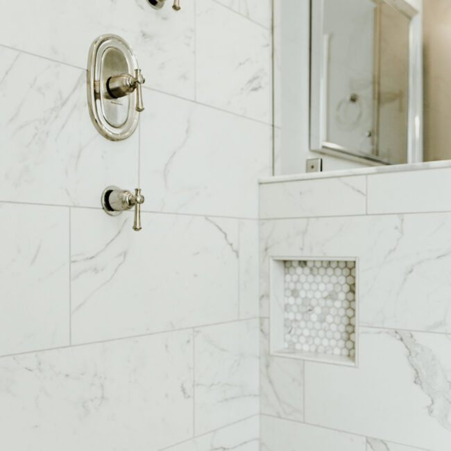Shower wall with mosaic niche and marble-look tile in Timeless Charm, a custom home by Mike Stevens Homes