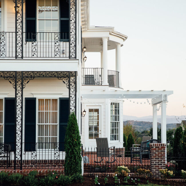 White Victorian-style home with iron balcony and pergola in Haunted Mansion Homage, a custom home by Mike Stevens Homes