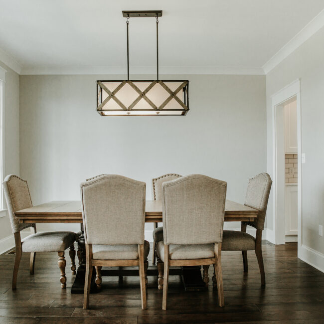 Dining room with rectangular chandelier and upholstered chairs in Timeless Charm, a custom home by Mike Stevens Homes