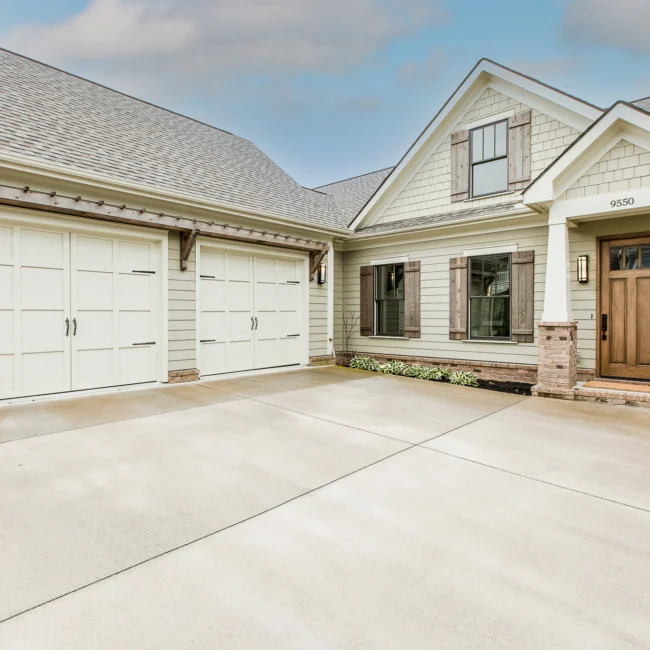 Three-car garage with white doors and stone-accent entry in Urban Farmhouse, a custom home by Mike Stevens Homes