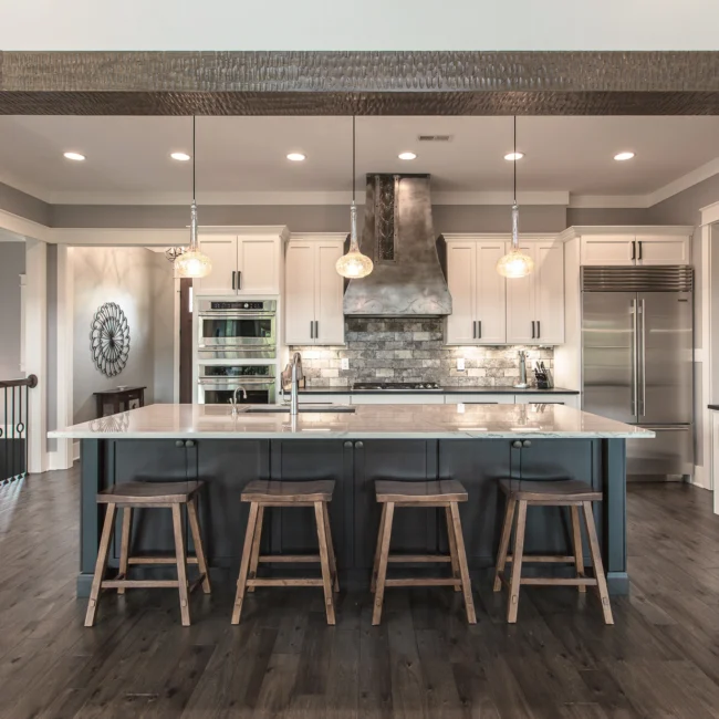Kitchen with black hood and dark island with seating in Urban Farmhouse, a custom home by Mike Stevens Homes
