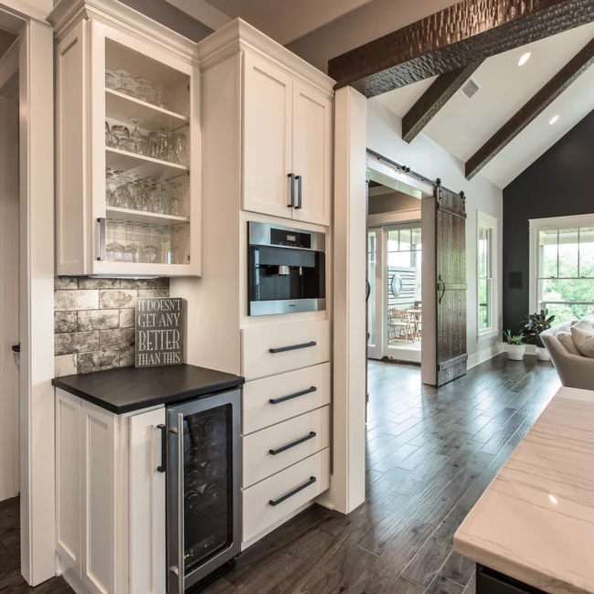 Wet bar with wine fridge and stone-clad backsplash in Urban Farmhouse, a custom home by Mike Stevens Homes