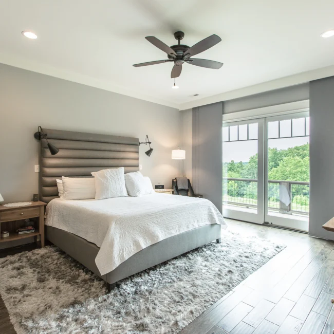 Primary bedroom with dark headboard and balcony doors in Urban Farmhouse, a custom home by Mike Stevens Homes