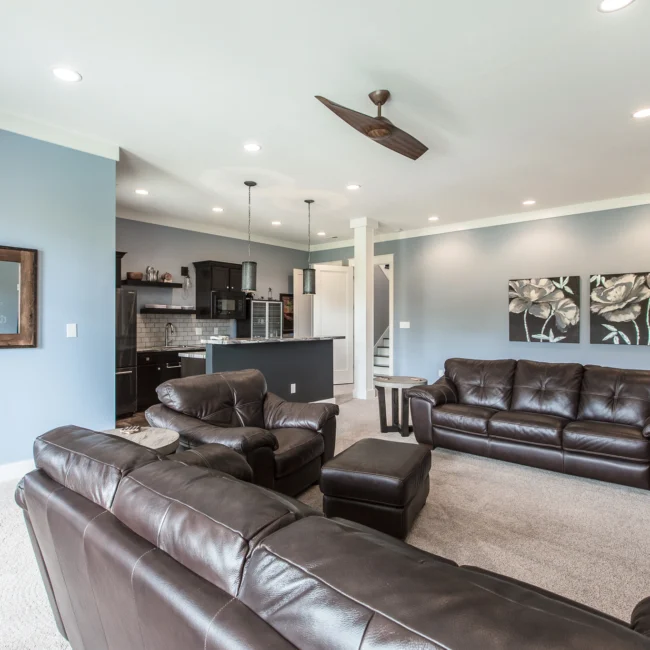 Family room with leather sectional and kitchen beyond in Urban Farmhouse, a custom home by Mike Stevens Homes