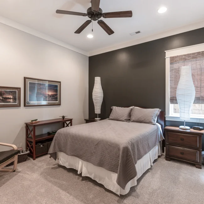 Bedroom with charcoal accent wall and bed in Urban Farmhouse, a custom home by Mike Stevens Homes