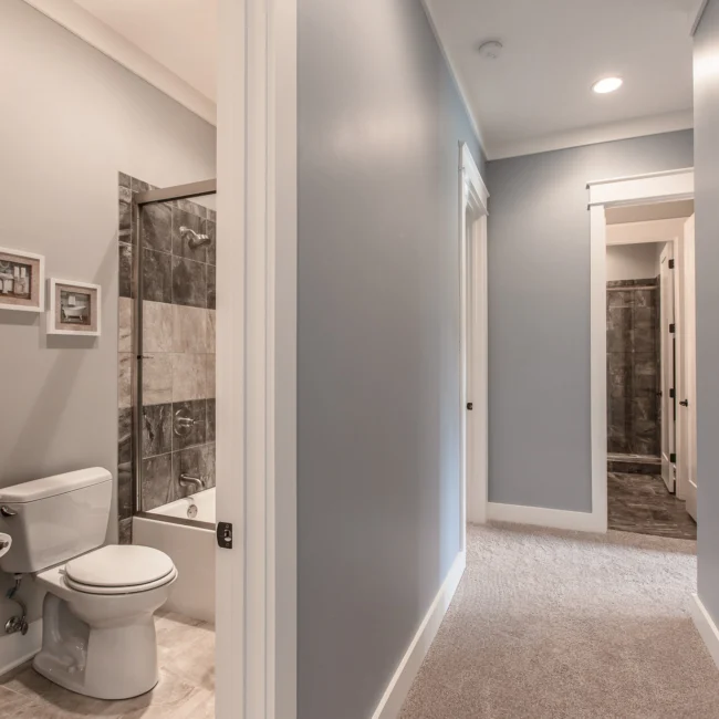 Hallway and bath with tub-shower and toilet in Urban Farmhouse, a custom home by Mike Stevens Homes