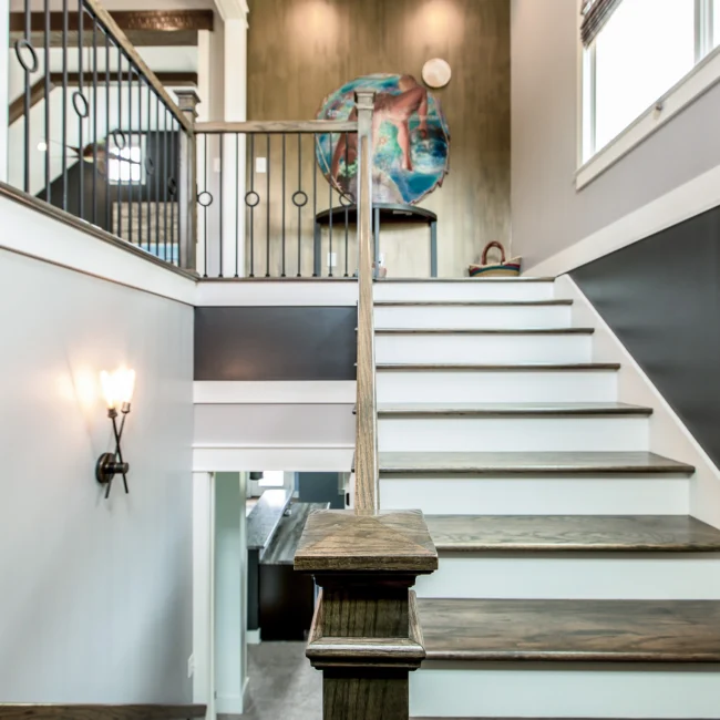 Staircase with black railing and wall sconce in Urban Farmhouse, a custom home by Mike Stevens Homes