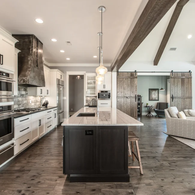Kitchen with dark island and black range hood in Urban Farmhouse, a custom home by Mike Stevens Homes