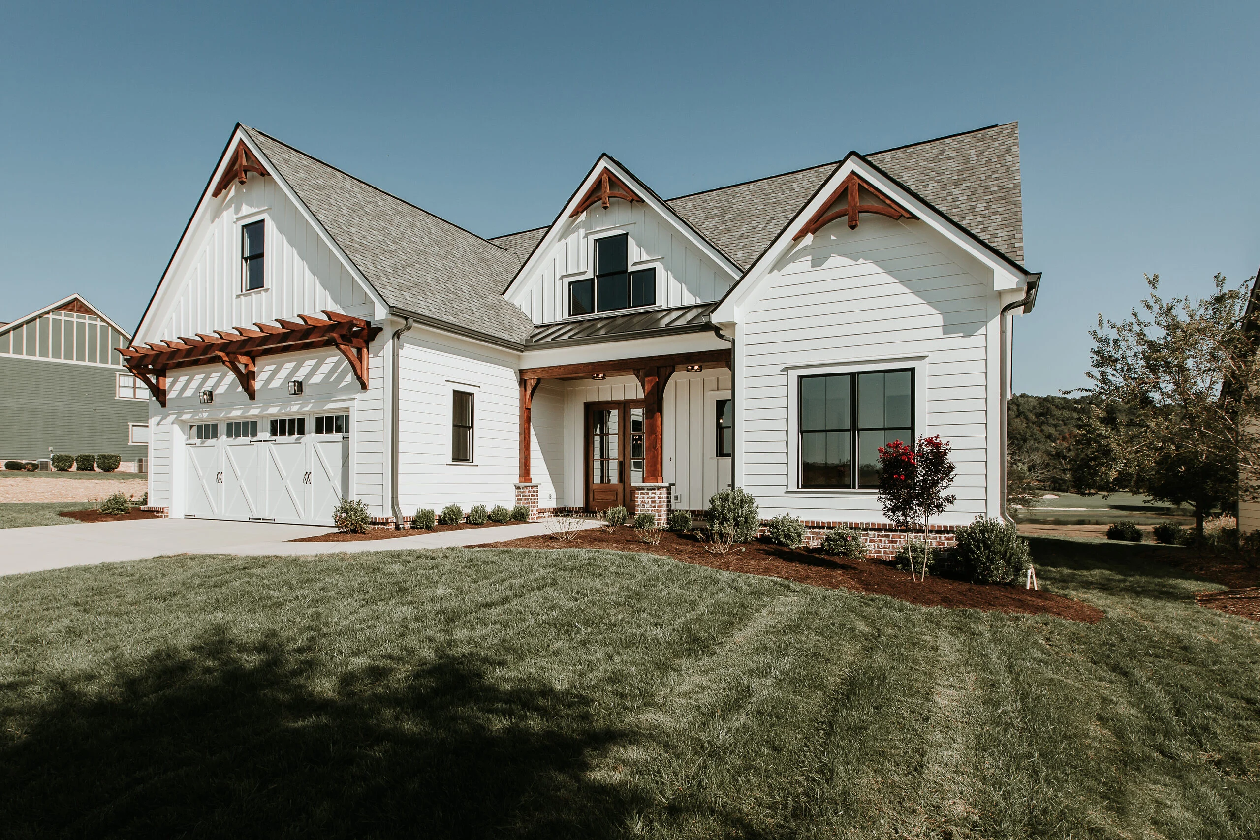 Front of white farmhouse with gables and wood brackets in Fairway Haven, a custom home by Mike Stevens Homes
