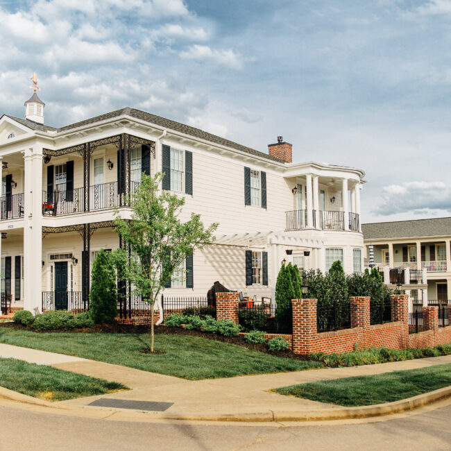 White home with iron balconies and brick garden wall in Haunted Mansion Homage, a custom home by Mike Stevens Homes