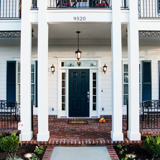Front entry with navy door, white columns and brick steps in Haunted Mansion Homage, a custom home by Mike Stevens Homes