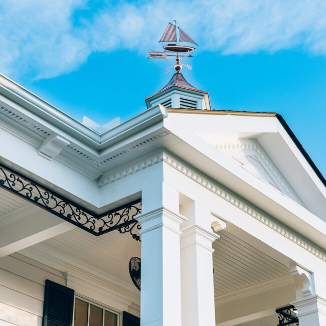 Cupola and weather vane above white pediment and iron trim in Haunted Mansion Homage, a custom home by Mike Stevens Homes