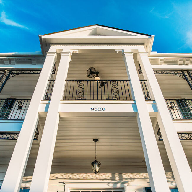 Looking up at white columns and porch ceiling fan in Haunted Mansion Homage, a custom home by Mike Stevens Homes