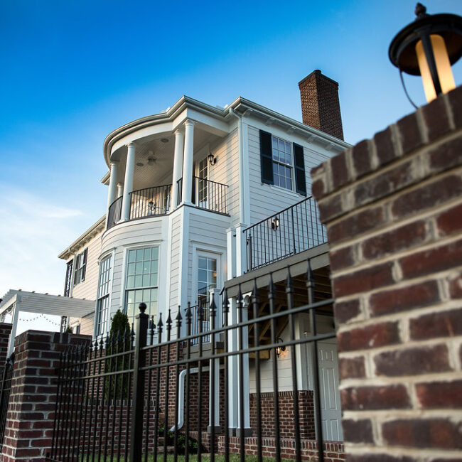Bay-window balcony and brick wall with iron railing at dusk in Haunted Mansion Homage, a custom home by Mike Stevens Homes