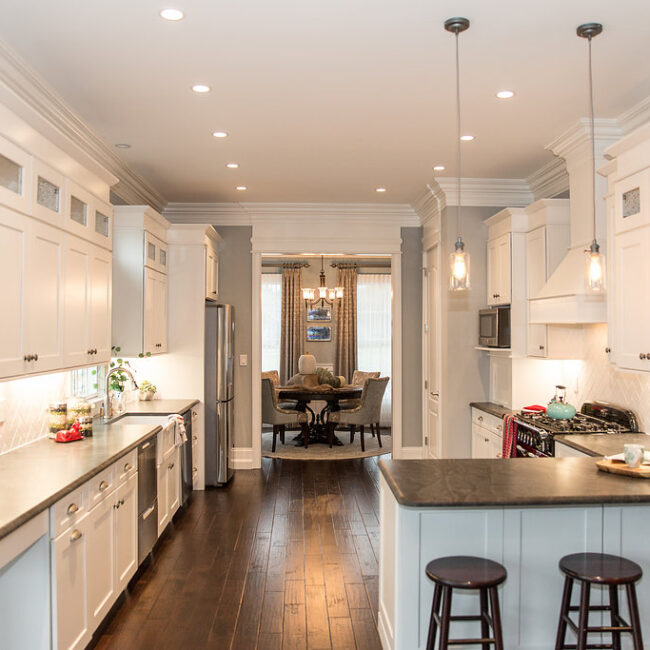 Galley kitchen with white cabinets, pendants and dark floors in Haunted Mansion Homage, a custom home by Mike Stevens Homes