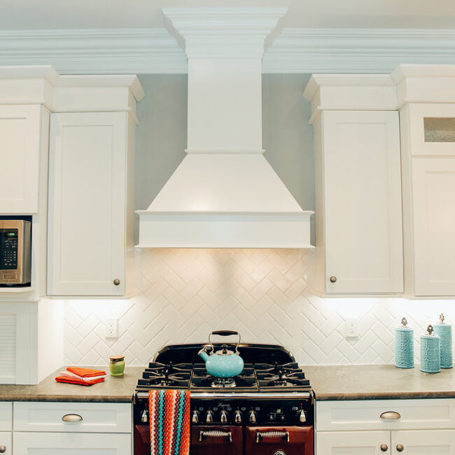 Kitchen with white range hood, subway tile and teal accents in Haunted Mansion Homage, a custom home by Mike Stevens Homes