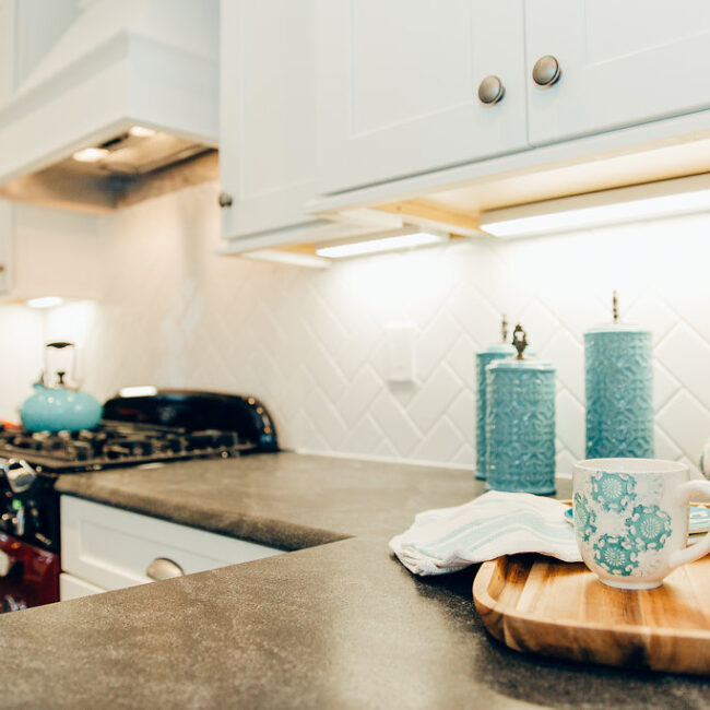 Close-up of dark range counter with teal decor and wood tray in Haunted Mansion Homage, a custom home by Mike Stevens Homes