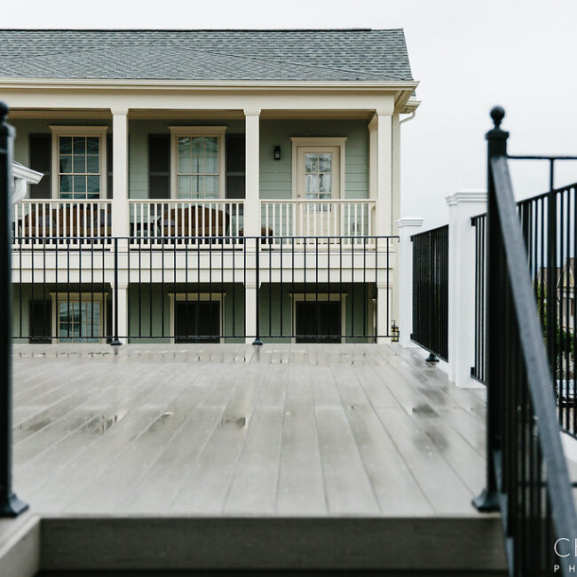 Back deck with gray wood floor and white balcony railing in Haunted Mansion Homage, a custom home by Mike Stevens Homes