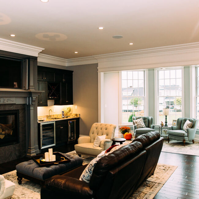 Great room with dark leather sofa, fireplace and windows in Haunted Mansion Homage, a custom home by Mike Stevens Homes