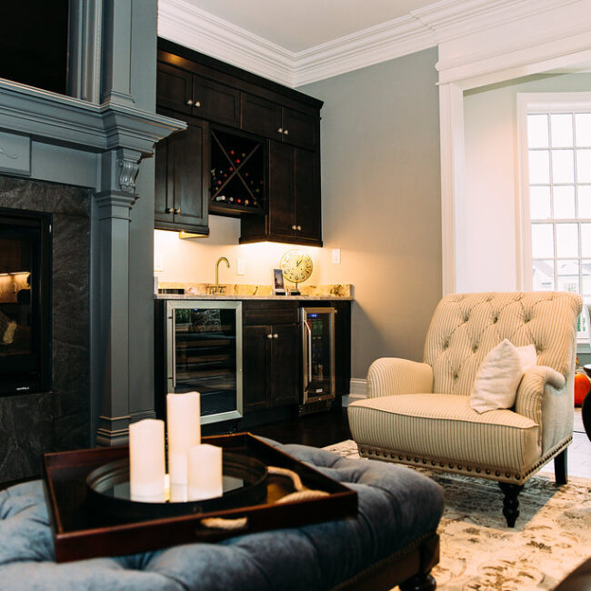 Built-in wine bar and fireplace beside tufted armchair in Haunted Mansion Homage, a custom home by Mike Stevens Homes