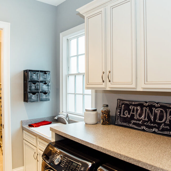 Laundry room with white cabinetry and Laundry sign in Haunted Mansion Homage, a custom home by Mike Stevens Homes