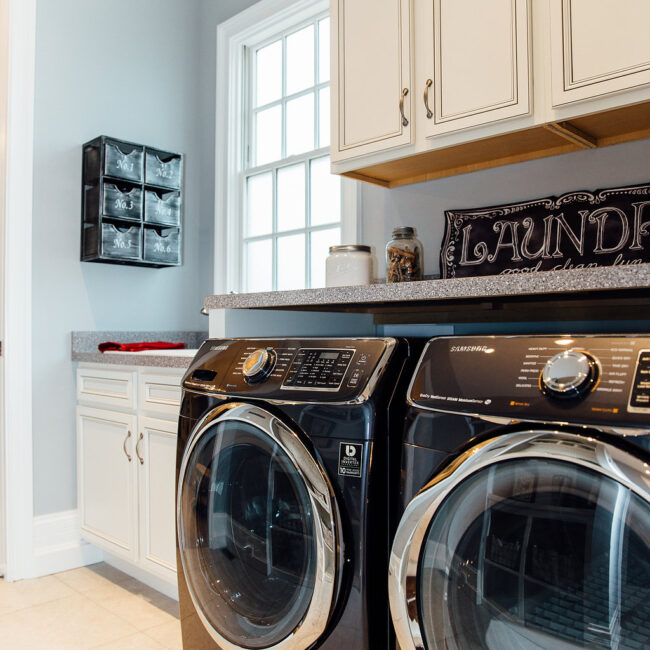 Laundry room with dark front-loading washer and dryer in Haunted Mansion Homage, a custom home by Mike Stevens Homes
