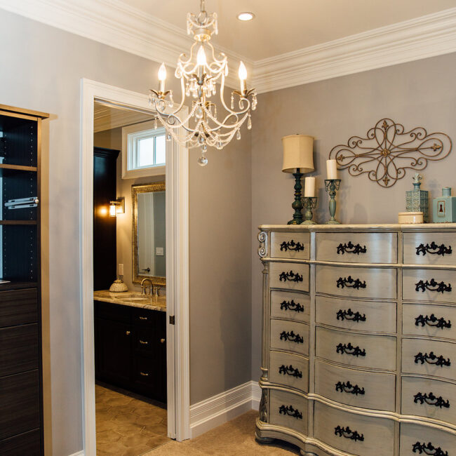 Primary bath entry with crystal chandelier and silver dresser in Haunted Mansion Homage, a custom home by Mike Stevens Homes
