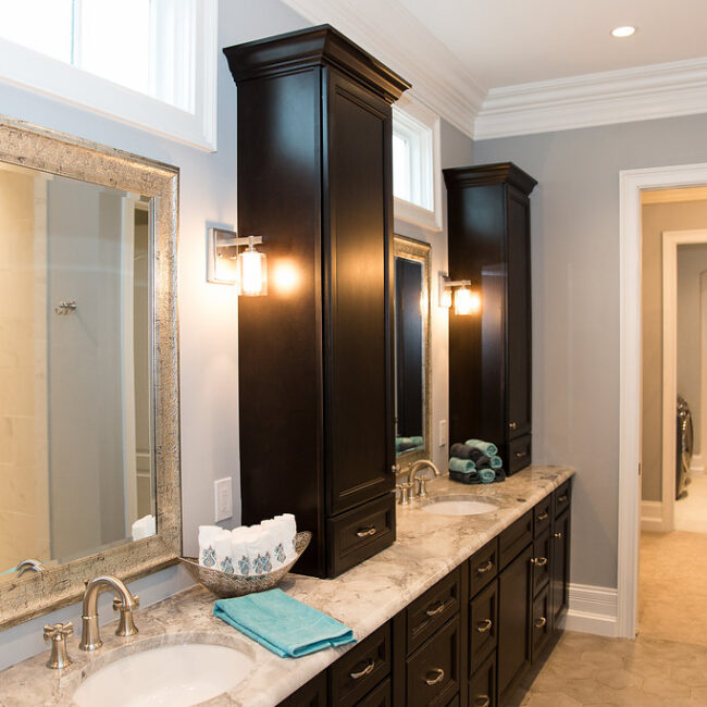 Dark wood double vanity with granite and wall mirrors in Haunted Mansion Homage, a custom home by Mike Stevens Homes