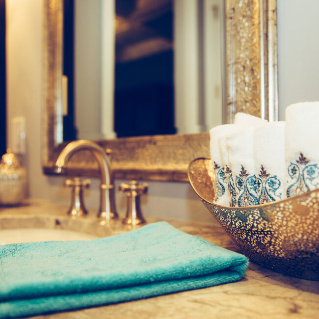 Close-up of gold vessel sink with teal hand towels in Haunted Mansion Homage, a custom home by Mike Stevens Homes