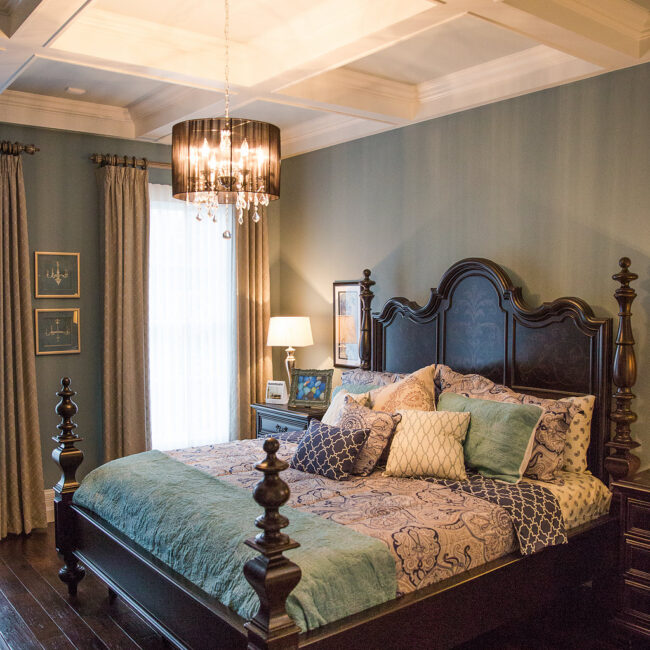 Primary bedroom with dark wood four-poster bed and chandelier in Haunted Mansion Homage, a custom home by Mike Stevens Homes
