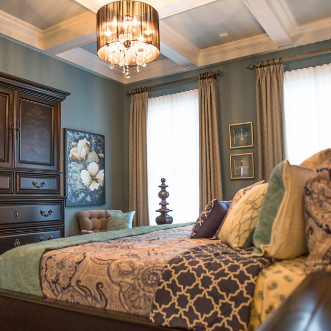 Bedroom with paisley bedding and coffered ceiling in Haunted Mansion Homage, a custom home by Mike Stevens Homes