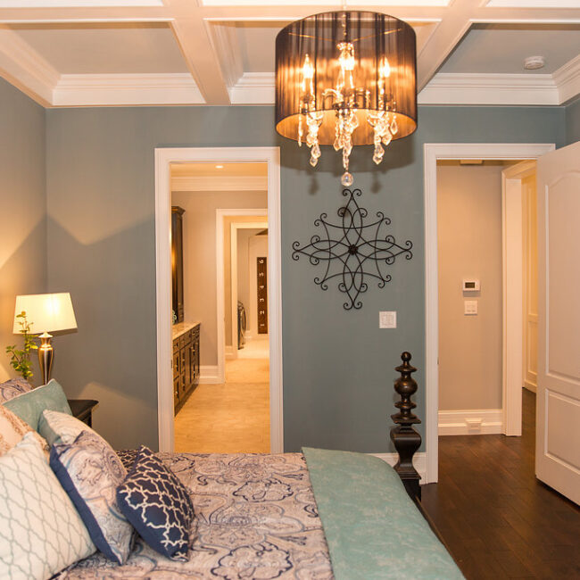 Bedroom with drum-shade chandelier and hallway view in Haunted Mansion Homage, a custom home by Mike Stevens Homes