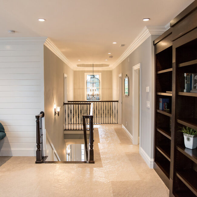 Hallway with shiplap wall, dark built-ins and iron railing in Haunted Mansion Homage, a custom home by Mike Stevens Homes