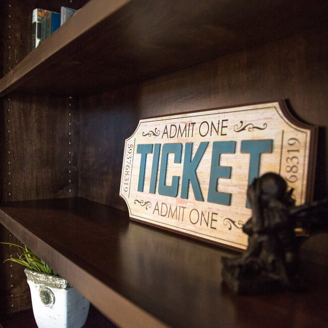 Vintage-style Admit One ticket sign on a dark shelf in Haunted Mansion Homage, a custom home by Mike Stevens Homes