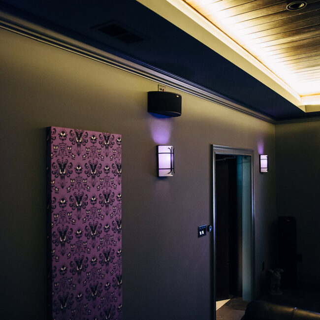 Home theater with purple patterned panels and wall sconces in Haunted Mansion Homage, a custom home by Mike Stevens Homes