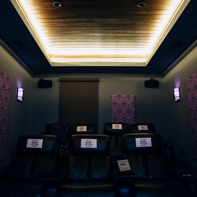 Home theater with reclining seats and tray ceiling lights in Haunted Mansion Homage, a custom home by Mike Stevens Homes