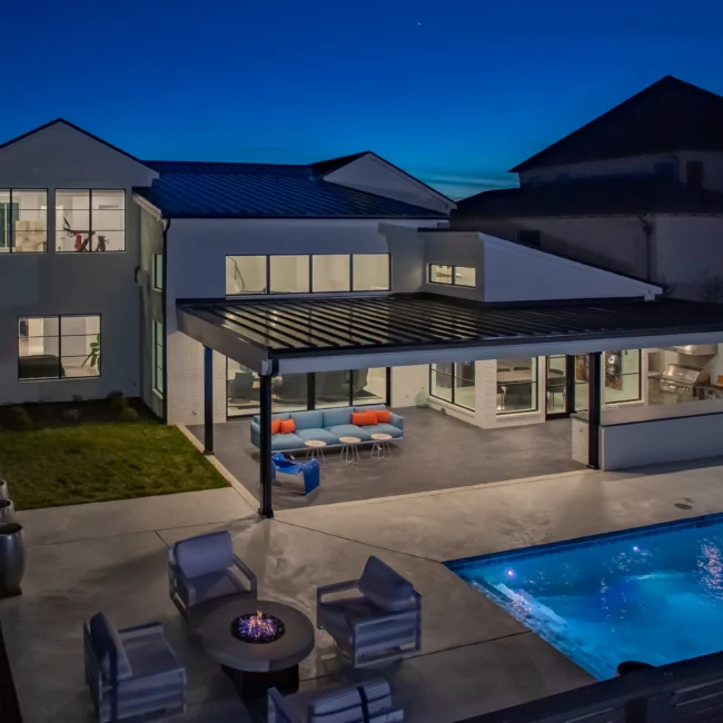Rear elevation at dusk with pergola over patio and pool in Urban Oasis by Mike Stevens Homes