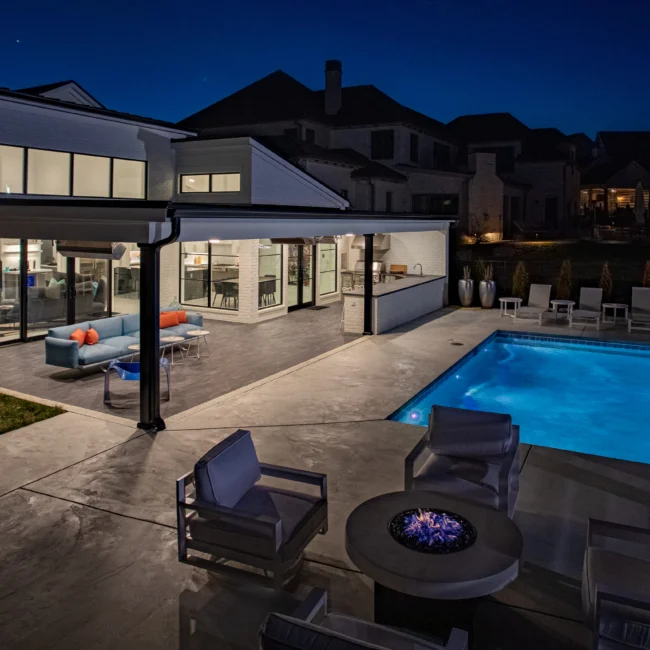 Patio with pergola, sofa seating and pool at dusk in Urban Oasis by Mike Stevens Homes