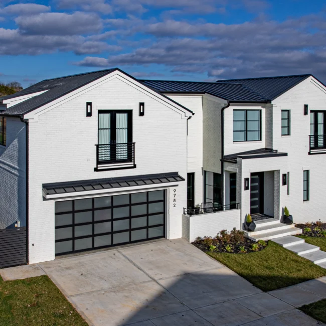 Front elevation of white brick home with black garage doors and gabled roof in Urban Oasis by Mike Stevens Homes