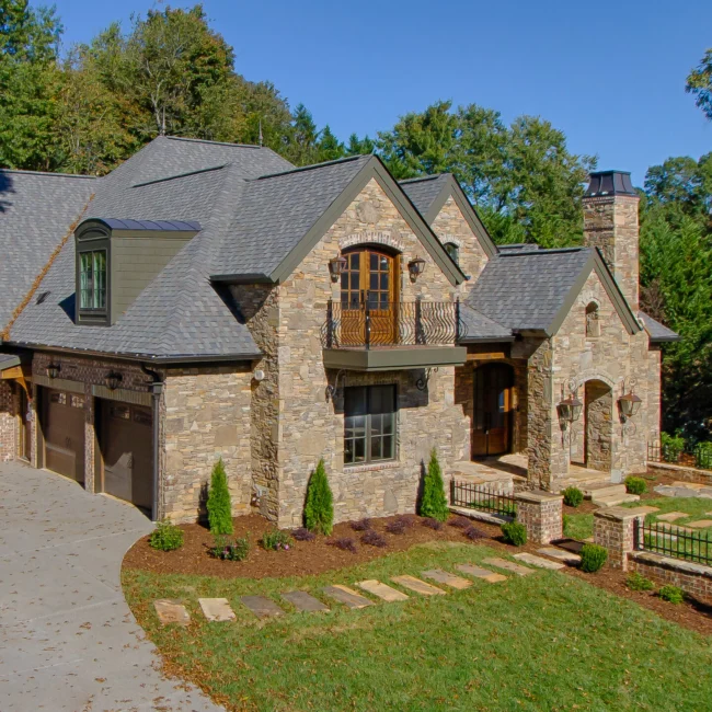 Stone and shingle exterior with gabled garage and arched entry in European Villa, a custom home by Mike Stevens Homes
